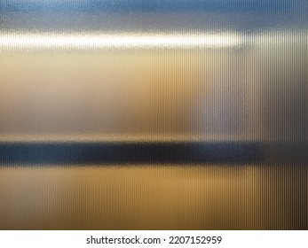 Frosted Wave glass vertical line pattern in the translucent effect of warm white light in wooden cupboard blurry inside. Slim and sleek line pattern glass close-up texture.