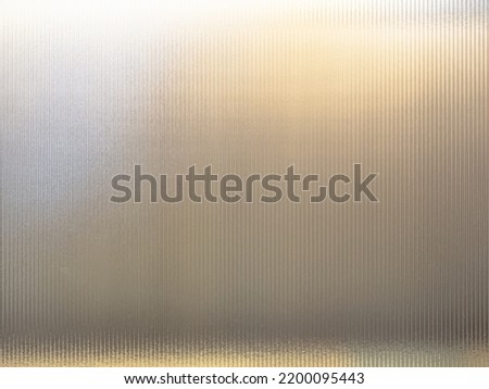 Frosted Wave glass vertical line pattern in the translucent effect of warm white light background. Slim and sleek line pattern glass close-up texture.