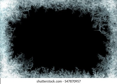 Frostwork. Decorative ice crystals on a window in form of a frame on black matte background