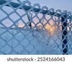 Frosty chain link fence in winter with winter sun