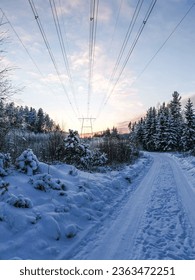 A frosty day in the winter season in Finland. The mast and power lines can be seen from the forest road - Shutterstock ID 2363472251