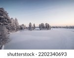 Frosty morning in the Finnish town of Kajaani in the north of the country in the Kainu region. A view of the frozen Kajaaninjoki river and the snowy forest near the river. Sunrise.