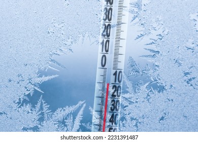 Frosty winter window with ice patterns and a thermometer showing a minus temperature.