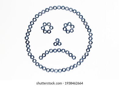 frowning emoticon made of metal nuts on a light background