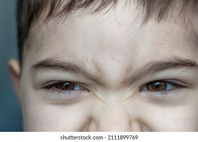 A Frowning Kid With Sad Eyes. Beautiful Big Brown Eyes With Long Lashes. Close Up Eyes Photo. Little Boy Emotions.