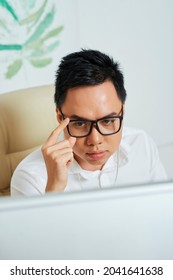 Frowning Serious Graphic Designer Adjusting Glasses When Reading Project Technical Requirements On Computer Screen