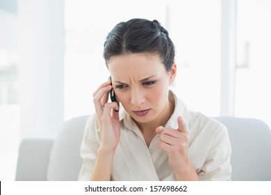 Frowning Stylish Brunette Businesswoman Making A Phone Call In Bright Office