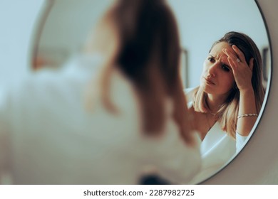 
				Frowning Woman Checking for New Wrinkles on her Forehead. Stressed businesswoman looking for fine lines and aging signs
				