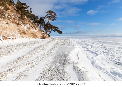 Frozen Baikal  Lake on a cold winter day. Beautiful landscape of a snowy beach near the coastal hills with picturesque pine trees on the shore. Winter travel. Natural background