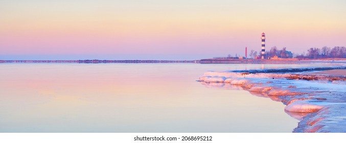 Frozen Baltic sea shore at sunset. Ice fragments and stones close-up. Lighthouse in the background. Colorful pink sky.Reflections on the water. Natural mirror. Latvia. Symbol of hope and peace - Powered by Shutterstock