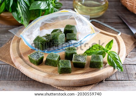 Frozen basil leaves (basilius) in ice cubes with fresh basil on a table. Frozen food concept