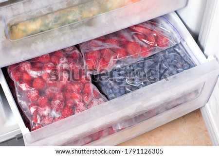 Frozen berries in plastic bags in the freezer. Open deep freeze filled with frozen berries