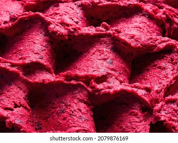 Frozen Black Currant flavour gelato - full frame detail of sorbet. Close up of a red surface texture of Ice cream filled with pieces of mixed fruit.