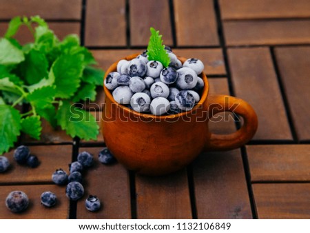 frozen blueberries in a clay cup on a wooden board table