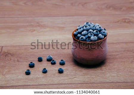 frozen blueberries in a clay cup on a wooden board table