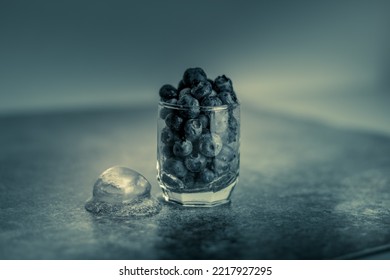 Frozen Blueberries In A Glass Cup On A Stone Background With Ice