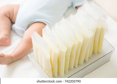 Frozen breast milk and leg of baby lying on the white bed