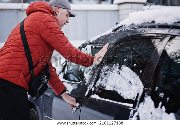 Frozen car door.\
Automobile car door or lock is frozen shut. Man driver trying to\
open frozen car door or\
lock