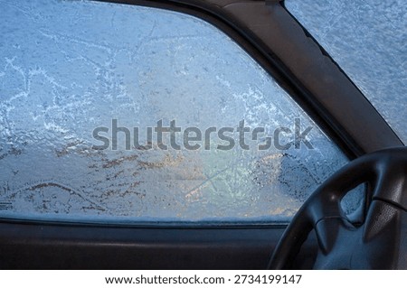 Frozen car side window covered with frost on cold winter morning