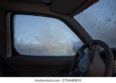 Frozen car window with ice patterns seen from inside vehicle interior