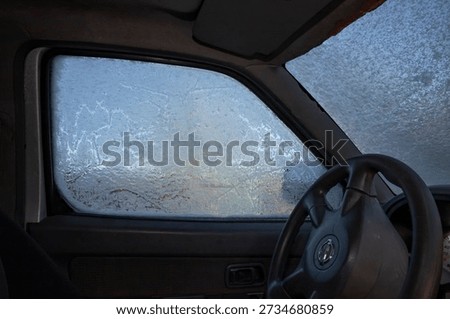 Frozen car window with ice patterns seen from inside vehicle interior