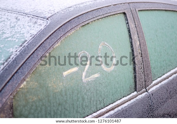Frozen car window with scratched text on the ice:\
\