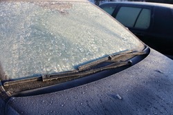 Frozen Car Windscreen With Wiper Blade And Hood On Frosted Windshield Glass. Autumn Morning Frosts