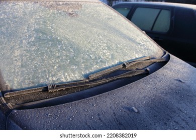 Frozen Car windscreen with wiper blade and hood on frosted windshield glass. Autumn morning frosts - Shutterstock ID 2208382019