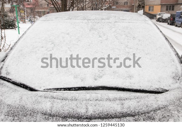 Frozen car windshield covered with ice and snow on\
a winter day. Close-up\
view.