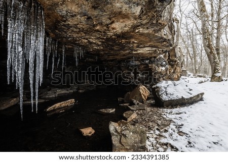 Frozen cave in snowy Sweden, adorned with shimmering icicles. Tranquil winter wonderland.