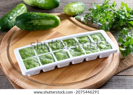 Frozen cucumber puree in ice cube trays ready for freezing on a cutting board on a wooden table. Frozen Food Concept.