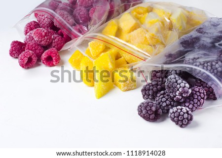 Frozen ecological berries in reusable plastic bags: raspberry, mango and blackberry. White background