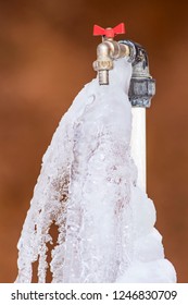 Frozen Faucet. Brown Background.