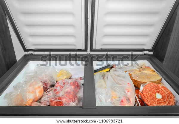 Frozen food in the freezer. Bagged frozen\
meat and other foods in a horizontal freezer with the two doors\
open. Food preservation.