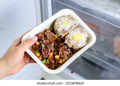 Frozen Food From The Freezer In The Female Hand, Woman Placing Container With Frozen Ready Meals In Refrigerator