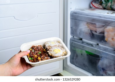 Frozen Food From The Freezer In The Female Hand, Woman Placing Container With Frozen Ready Meals In Refrigerator