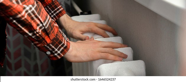 Frozen Hands Touch A Heating Battery At Home During Winter Season