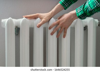 Frozen Hands Touch A Heating Battery At Home During Winter Season