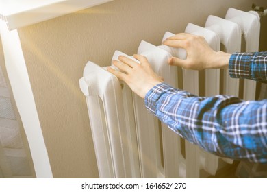 Frozen Hands Touch A Heating Battery At Home During Winter Season