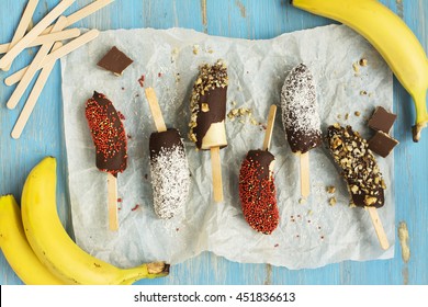 Frozen Homemade Banana Pops Covered With Chocolate, Sprinkles, Nuts And Coconut Chips. Top View