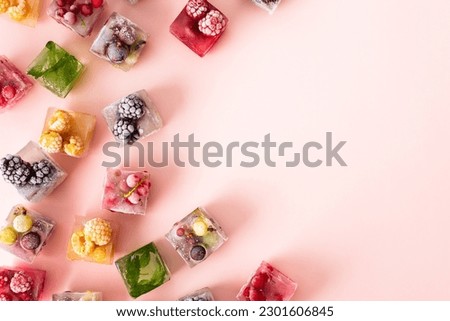 Frozen ice cubes with various fruits, blackberries and raspberries, gooseberries and currants, blueberries and mint, top view
