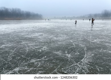 Frozen Lake With People Skating In The Distance