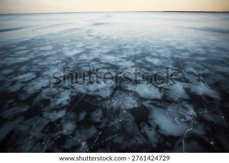 Frozen Lake at Sunset with Ice Patterns and Cracks