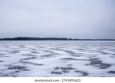 Frozen lake surface covered with patterned ice and snow during winter