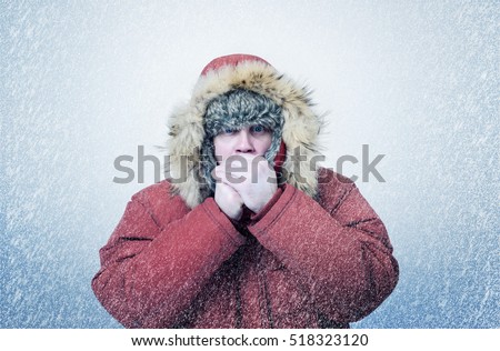 Frozen man in winter clothes warming hands, cold, snow, blizzard