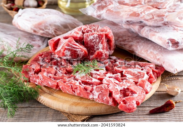 Frozen meat in a plastic bag on a wooden table.\
Frozen food.