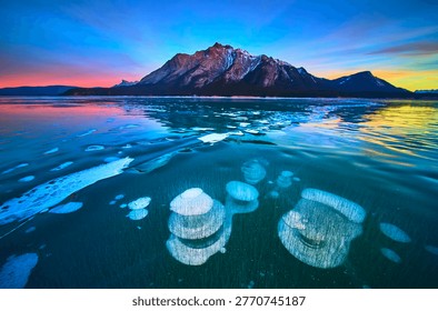 Frozen Methane Bubbles and Mountain Reflections on Winter Lake at Sunset