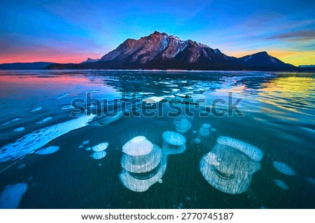 Frozen Methane Bubbles and Mountain Reflections on Winter Lake at Sunset