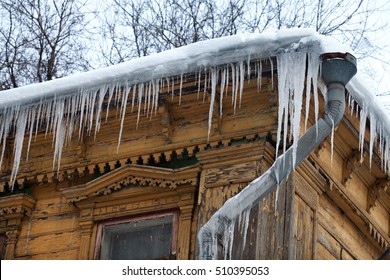 Frozen Mysterious Mansion With Water Pipe And Frozen Icicles On The Roof, Top Floor Wooden Mansion. Icy Weather Winter Scene