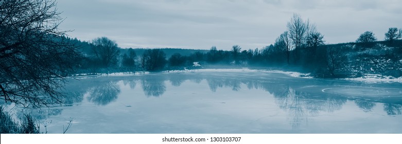 Frozen pond, thaw. Winter season in the countryside. Web banner. Postcard design. Ukraine. Europe.